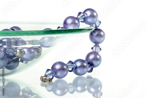 Purple necklace hanging from glass bowl