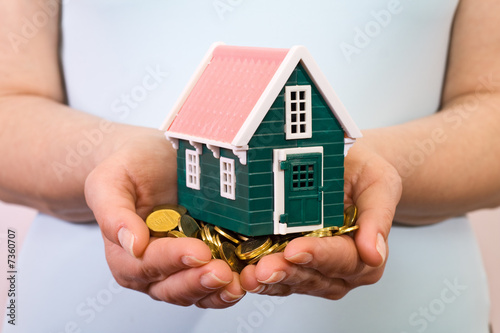 House on a pile of money in woman hands