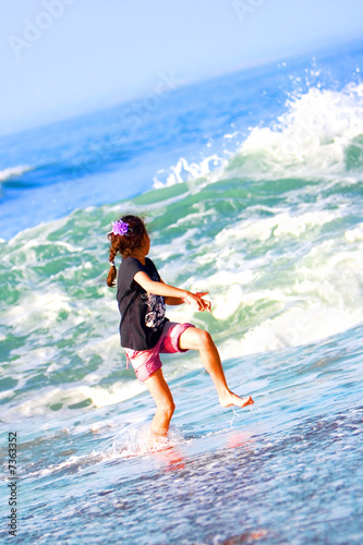 Excited young girl, ready to sprint up the beach from waves