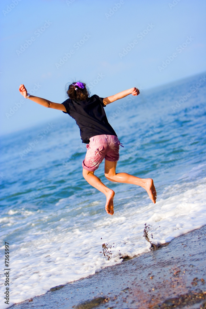 Girl jumps above crashing waves on the beach. Girl jumps above crashing waves on the beach.