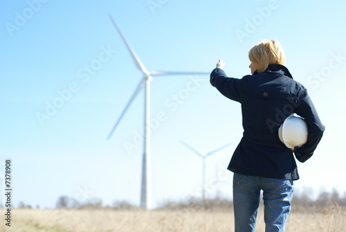 Woman engineer with white safety hat and wind turbines © Andrei Merkulov