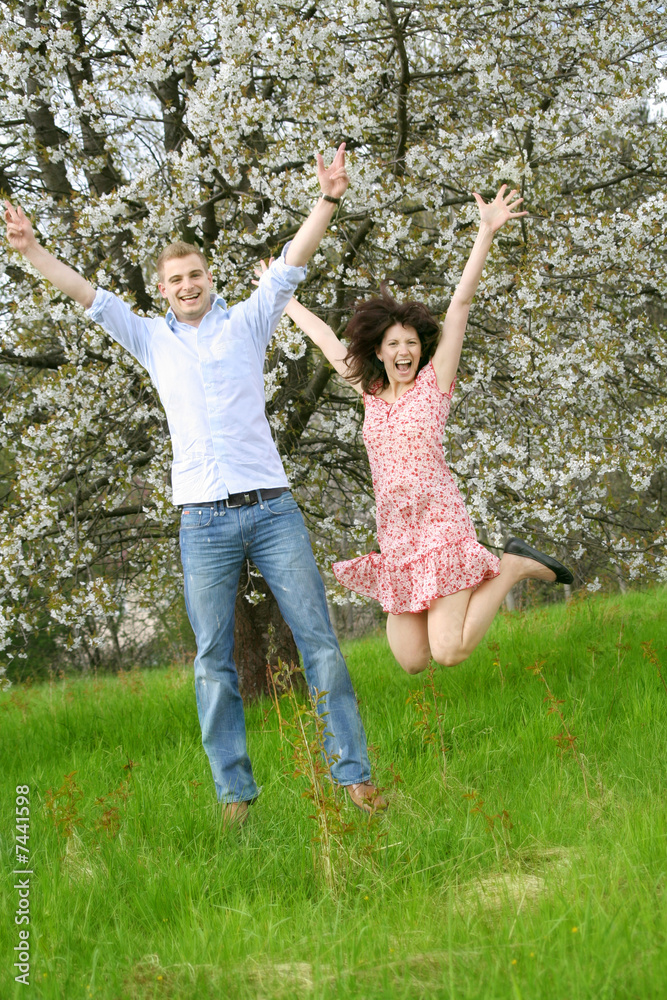 Obraz premium young and happy couple is jumping on a meadow