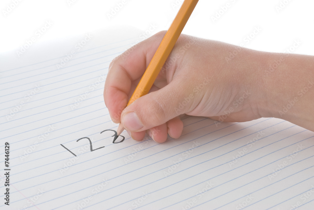 Child's hand holding pencil, writing numbers on paper Child's hand holding pencil, writing numbers on paper