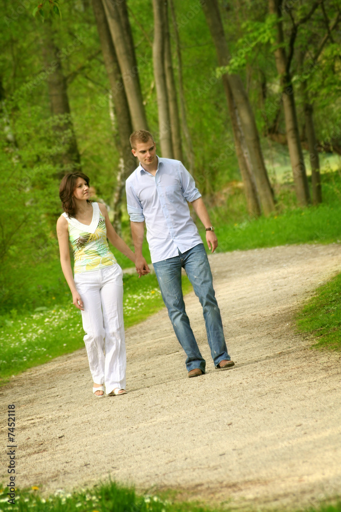 young and happy couple taking a walk in a park
