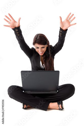 Happy business woman sitting on the ground with laptop