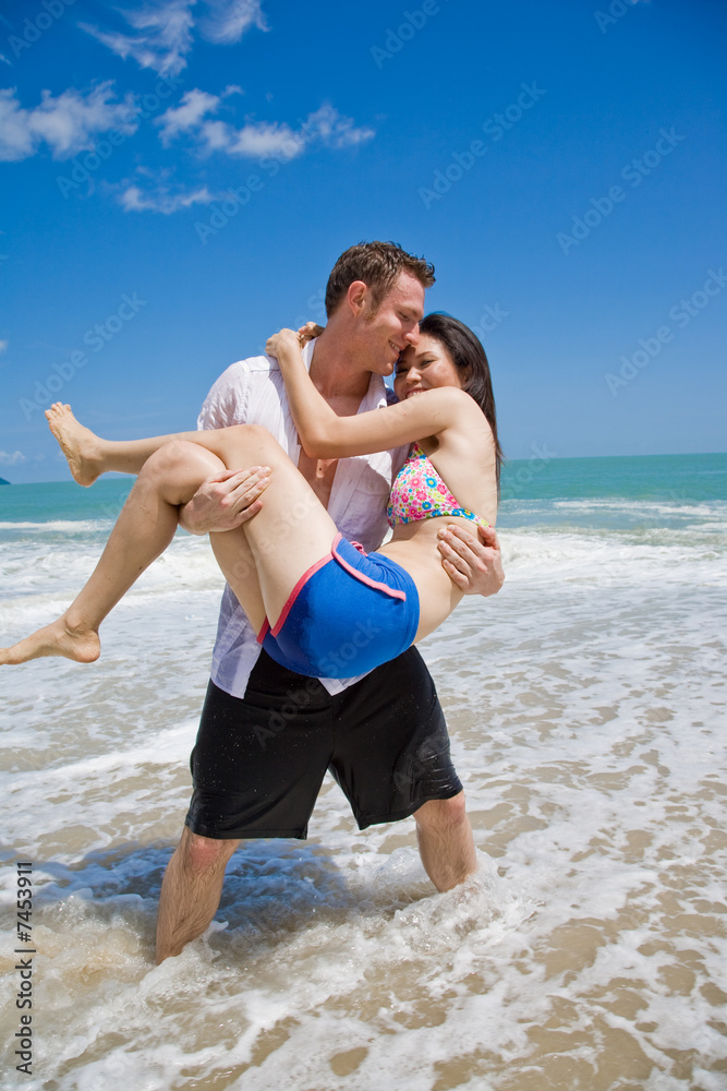 hunky caucasian man carrying gorgeos girl on the beach hunky caucasian man carrying gorgeos girl on the beach
