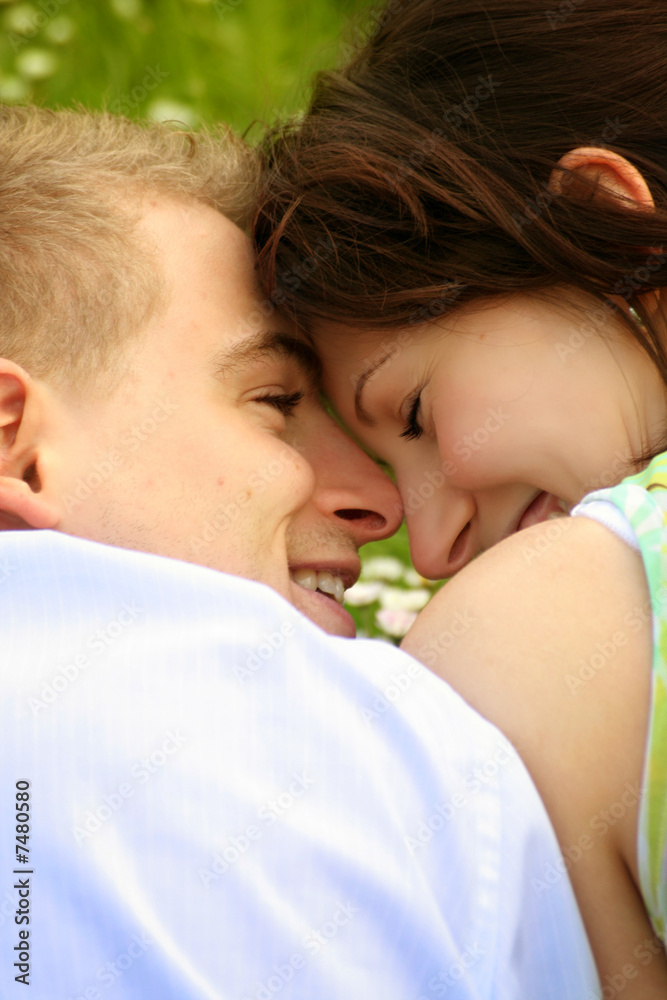 young and happy couple is smiling on a meadow