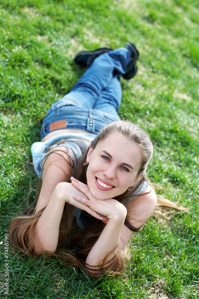 Smiling girl lying an green grass at sunshine Smiling girl lying an green grass at sunshine