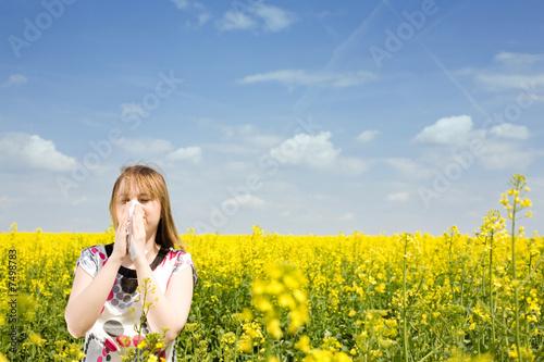 Young woman blowing her nose on the rape field