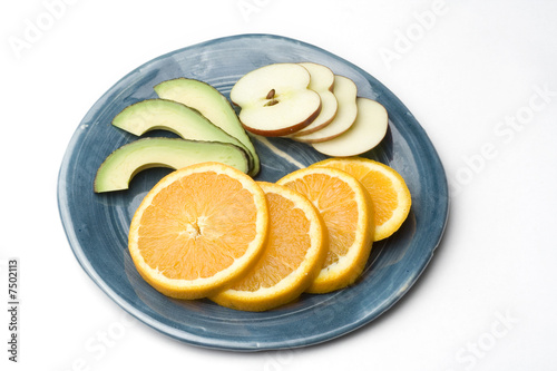 a blue plate with slices on orange apple and avocado