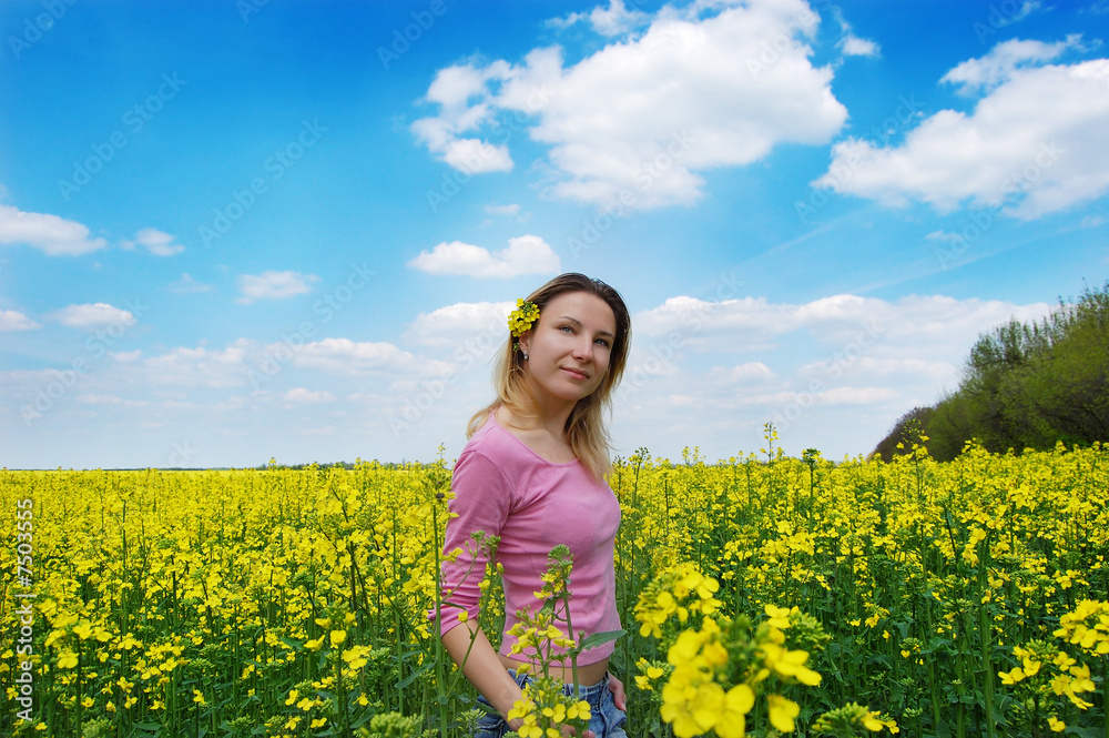 Fototapeta premium Beautiful girl among blooming rape oilseed field