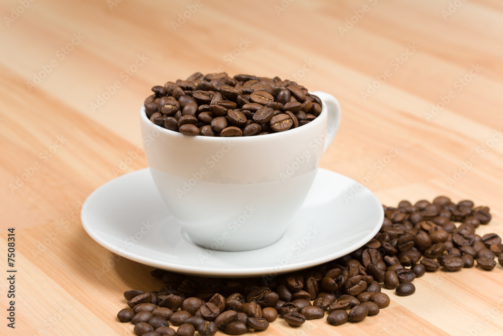 Cup with freshly roasted coffee beans on hardwood floor