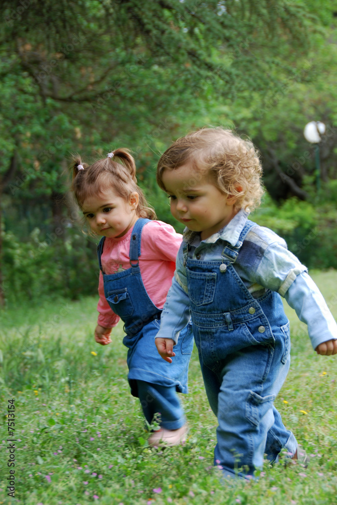 un petit garçon et une fillette qui se promène dans un parc un petit garçon et une fillette qui se promène dans un parc