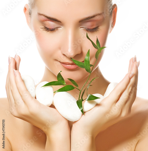 Beautiful young woman holding plant growing up through stones