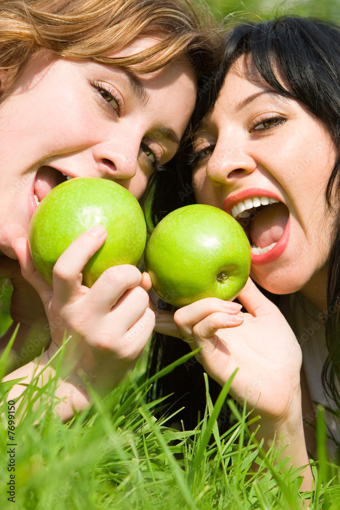 pretty women eating green apples on the summer glade pretty women eating green apples on the summer glade