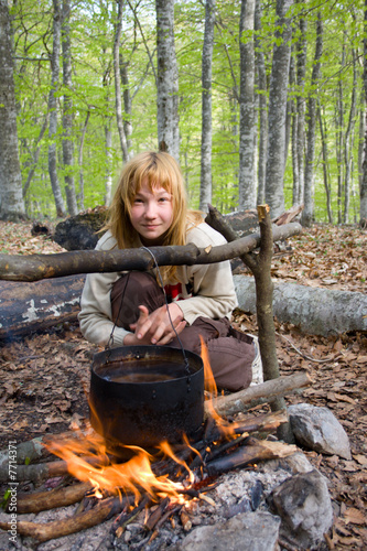 Girl sitting near of bonfire in forest