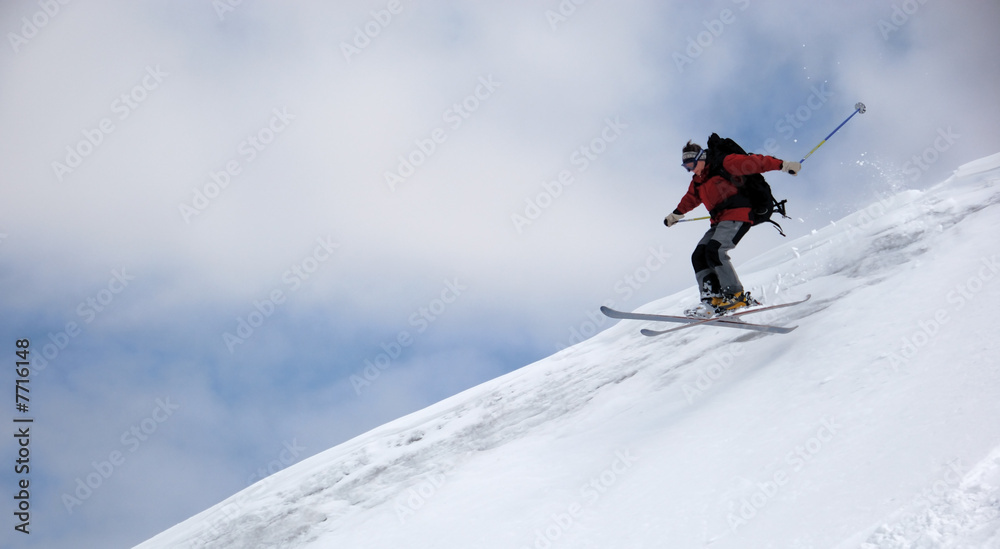 Skier jumping from the edge of snow ridge