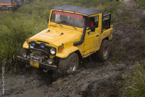 A yellow jeep splattered and caked with mud © Herjua