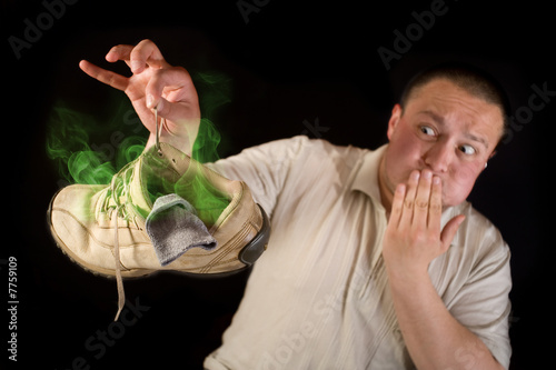 Shocked man holding smelling shoe