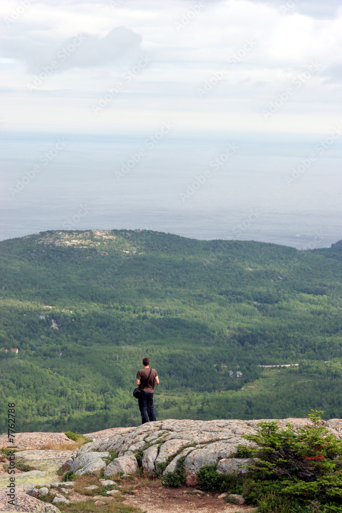 Solitary hiker standing on a granite mountaintop