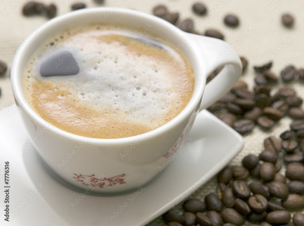 Cup of coffee and grains over sackcloth