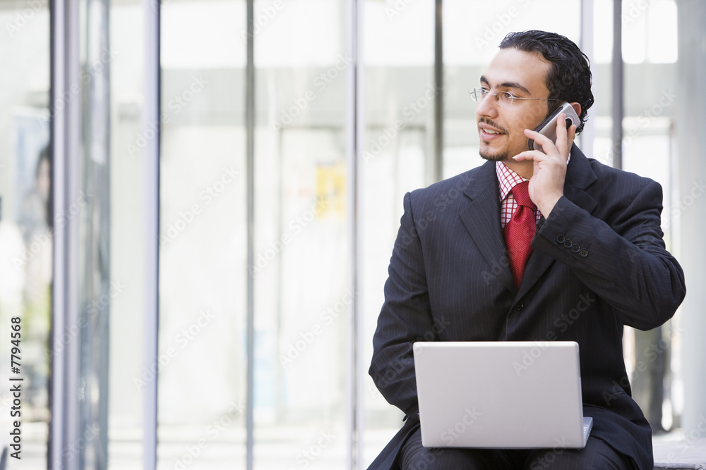 Businessman using laptop and mobile phone outside Businessman using laptop and mobile phone outside