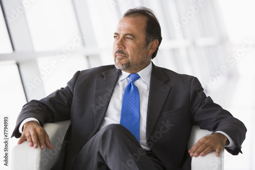 Canvas Print Businessman sitting in chair in lobby