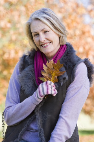 Senior woman holding autumn leaf outdoors