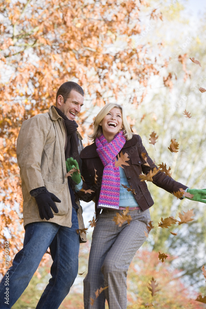 Fototapeta premium Young couple having throwing leaves in the air
