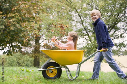 Young boy pushing girl in wheelbarrow