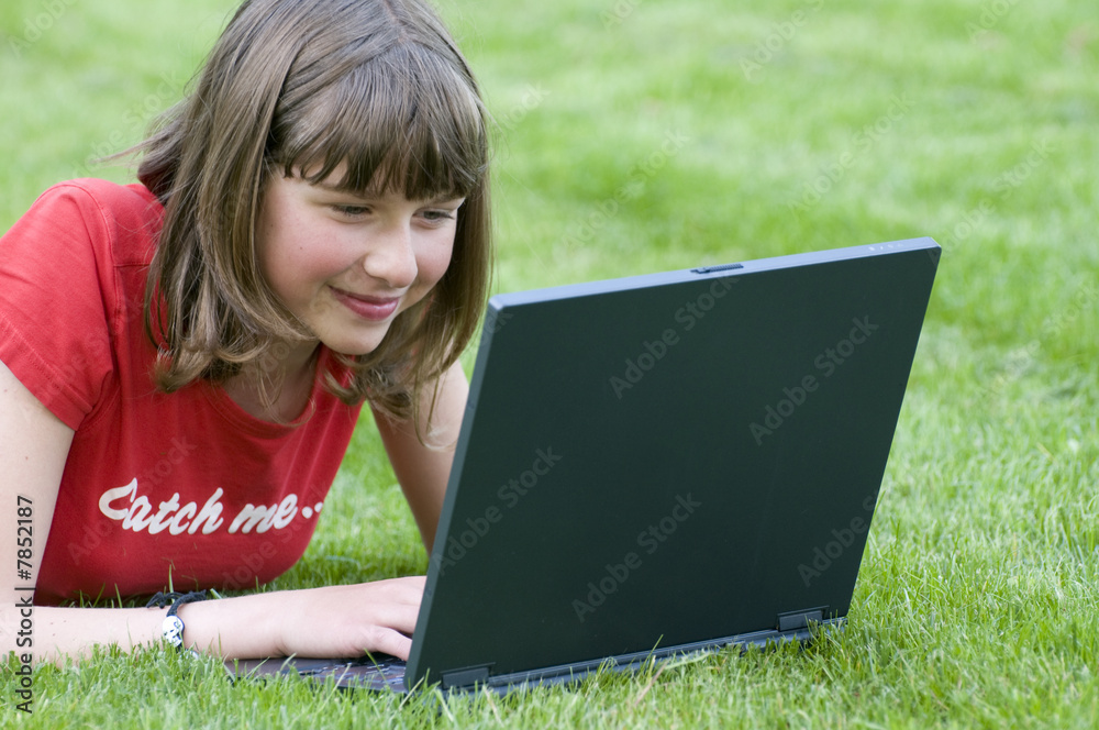 Teenager working at computer on the grass Teenager working at computer on the grass