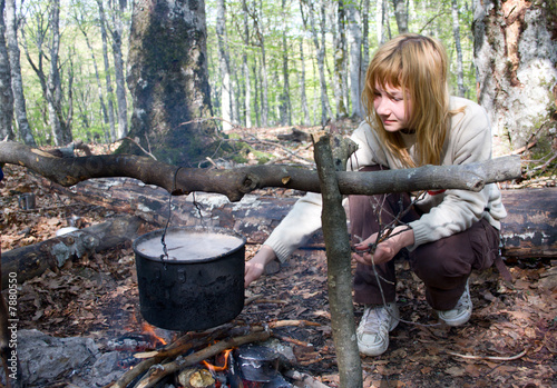 Girl cooking food on fire in camp