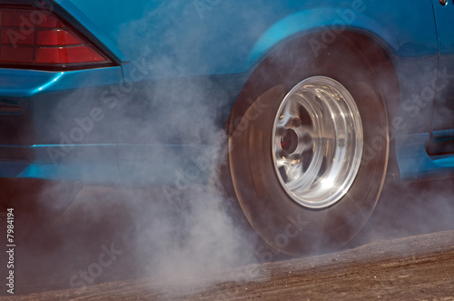 Smoke from the tires of a blue-green racer