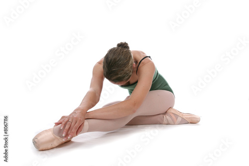 Pretty ballerina stretching against a high key background.