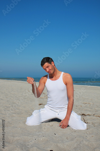 brünetter mann am strand spielt mit sand vergehende zeit photo