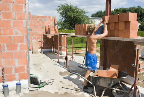builder putting bricks on scaffolding
