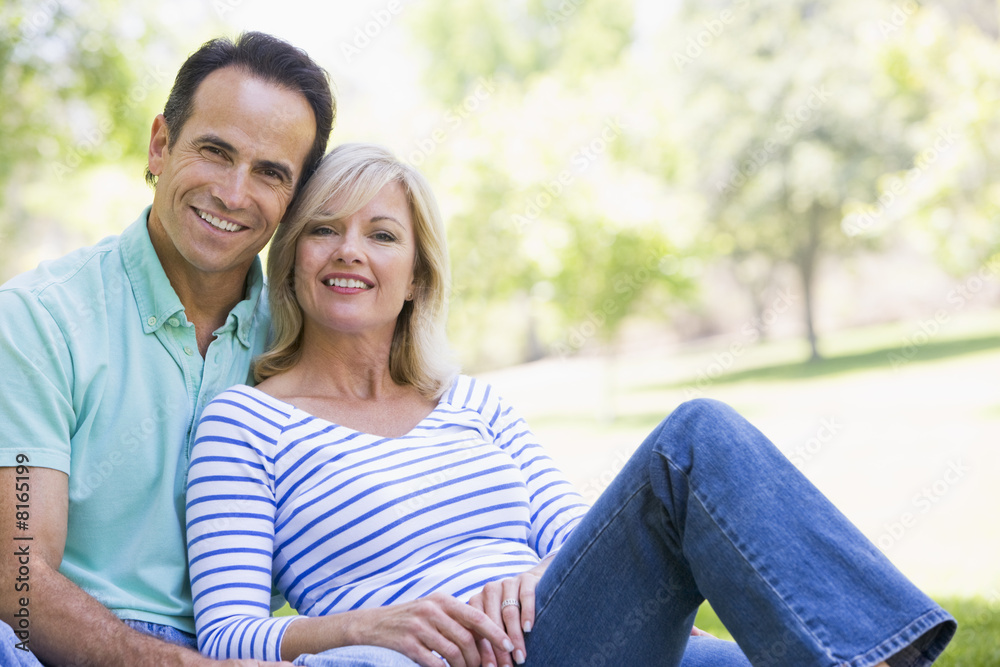 Couple relaxing outdoors in park smiling