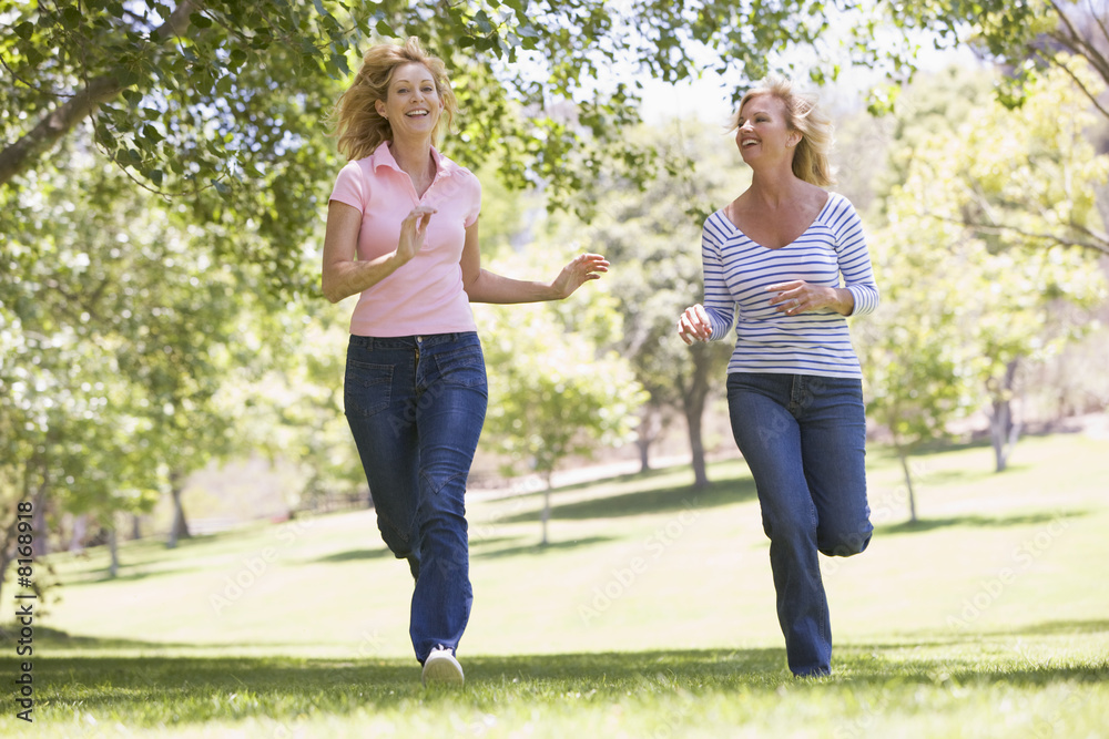 Two women running in park and smiling Two women running in park and smiling