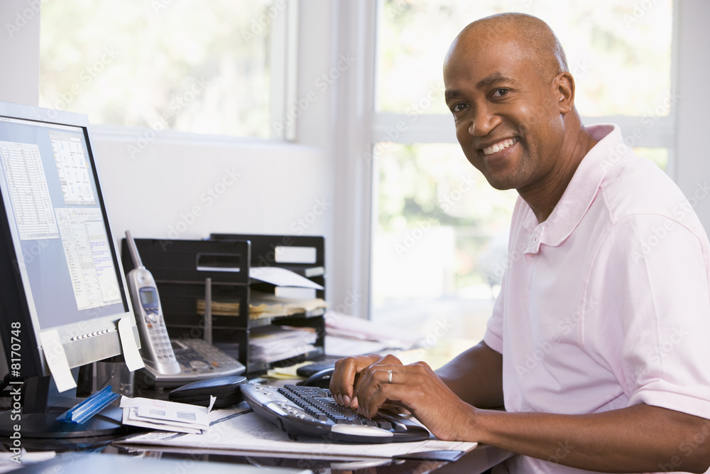 Man in home office using computer and smiling Man in home office using computer and smiling