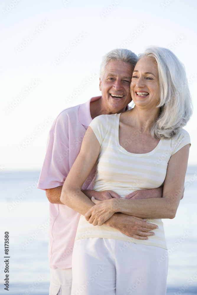 Obraz premium Couple at the beach embracing and smiling