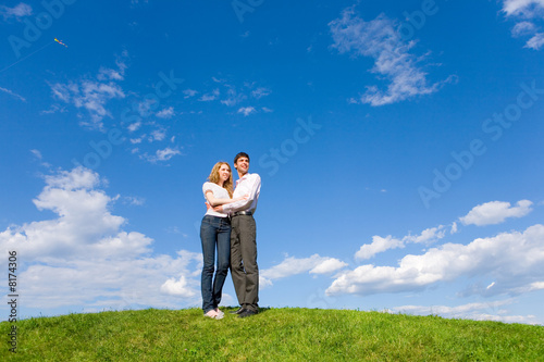Happy young couple looking at something above a green meadow