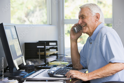 Man in home office on telephone using computer