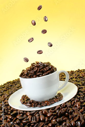 Coffee beans falling over a coffee cup