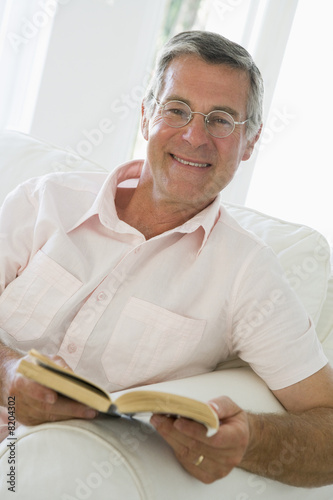 Man in living room reading book smiling