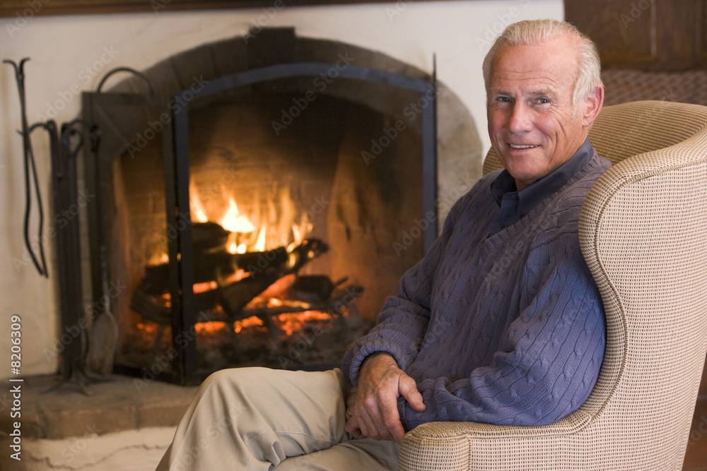 Man sitting in living room by fireplace smiling Man sitting in living room by fireplace smiling