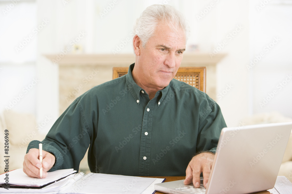 Man in dining room with laptop and paperwork Man in dining room with laptop and paperwork