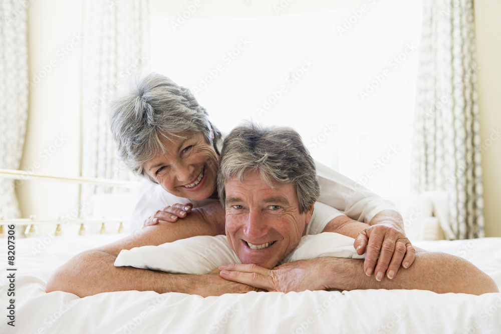 Couple lying on bed together smiling Couple lying on bed together smiling