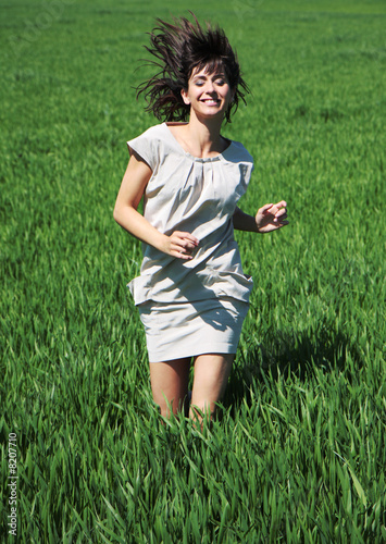 happy woman running throught green meadow grassland