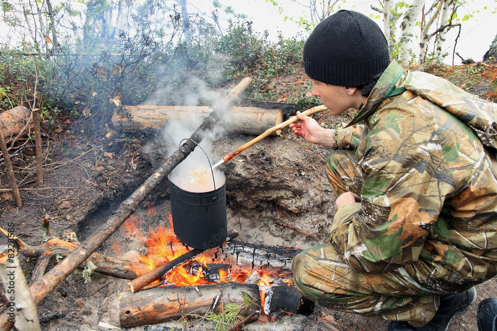 The teenager cooks I food on a fire