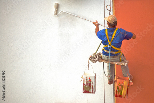 Hanging Painter painting wall with roller photo